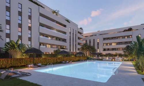 Vista nocturna de la piscina de diseño de Insur Iris. Se aprecia la iluminación led bajo el agua, las zonas de descanso con sombrillas de brezo y el ambiente relajado de las zonas comunes premium frente al edificio iluminado.